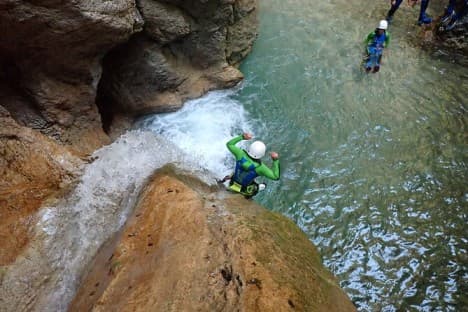 Adventurer jumping from a rock into deep water on the intermediate Titan canyoning route