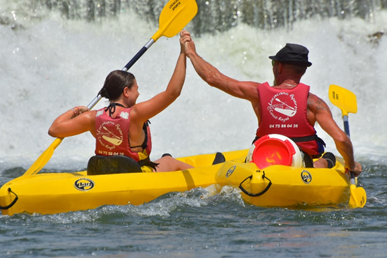 Two kayakers sharing a celebratory high-five on the Ardèche river after completing their route